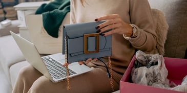hand-holding-purse-near-laptop